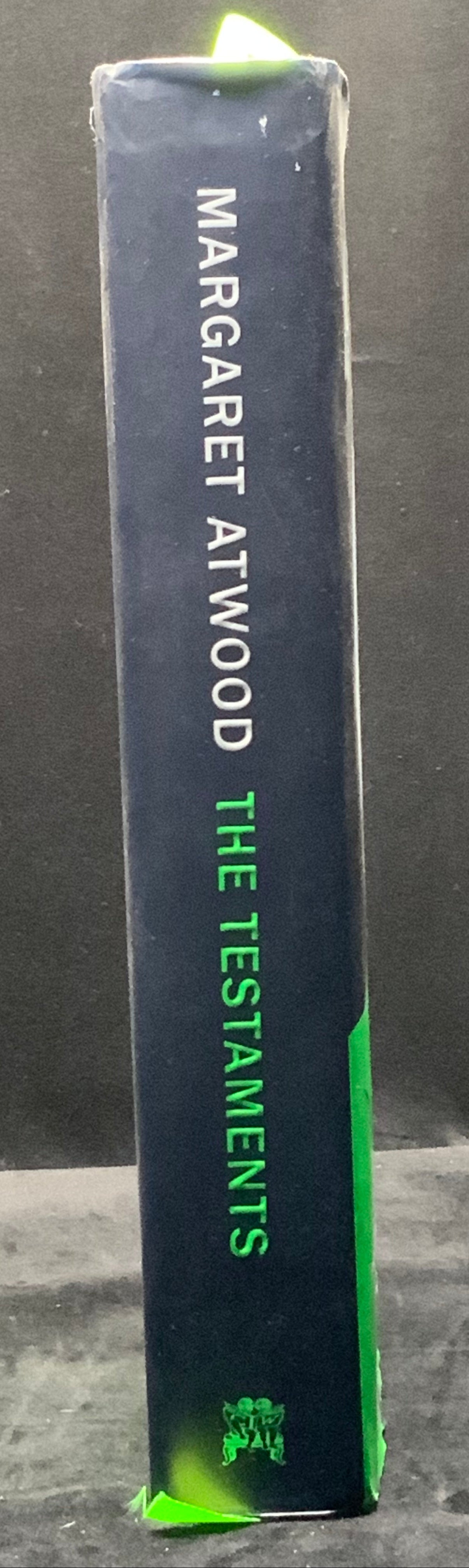 Book titled 'The Testaments' by Margaret Atwood on a dark surface