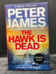 Book titled 'The Hawk is Dead' by Peter James with a signed copy label on a dark background