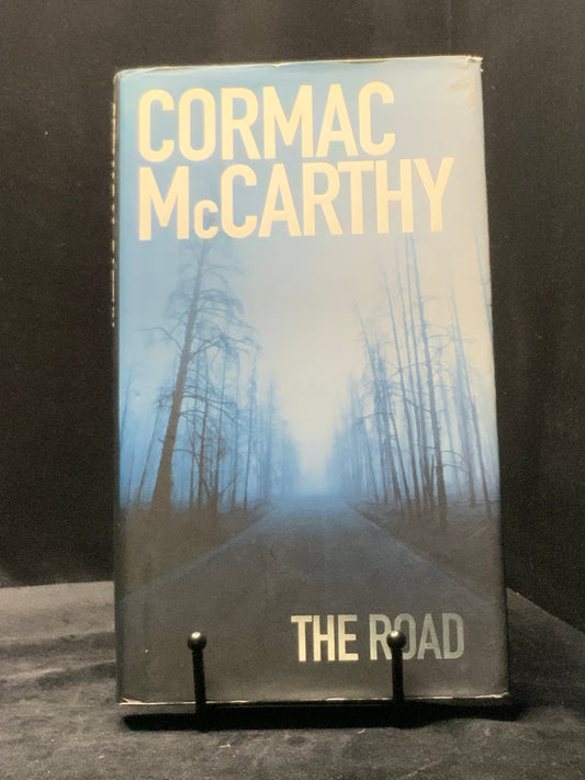 Book titled 'The Road' by Cormac McCarthy on a dark background