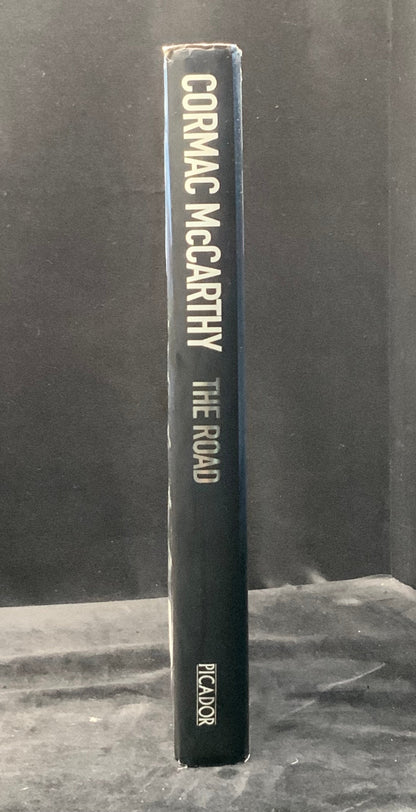 Book titled 'The Road' by Cormac McCarthy on a dark background