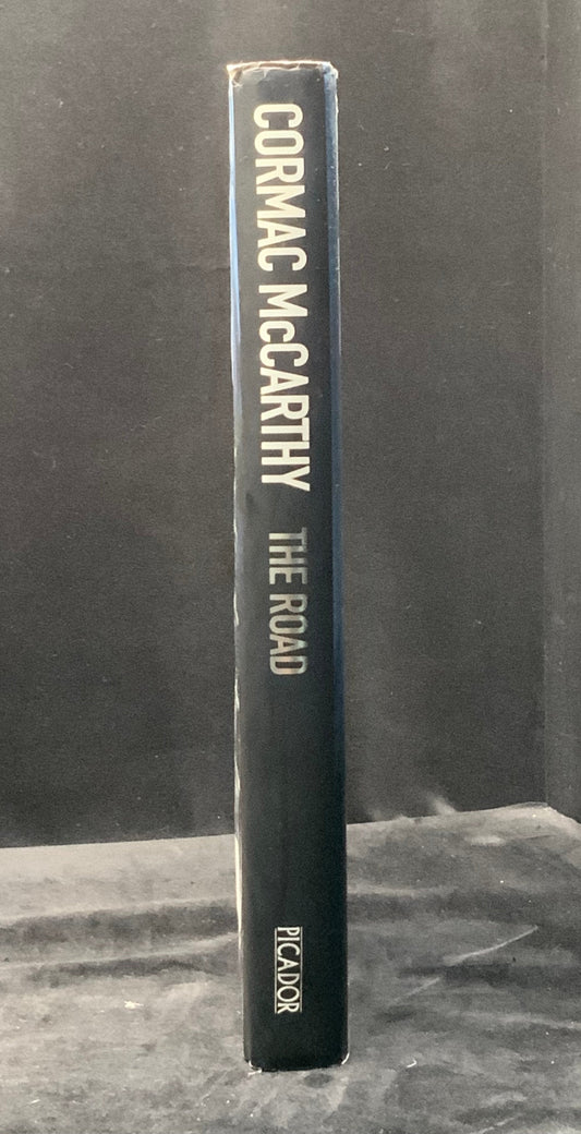 Book titled 'The Road' by Cormac McCarthy on a dark background