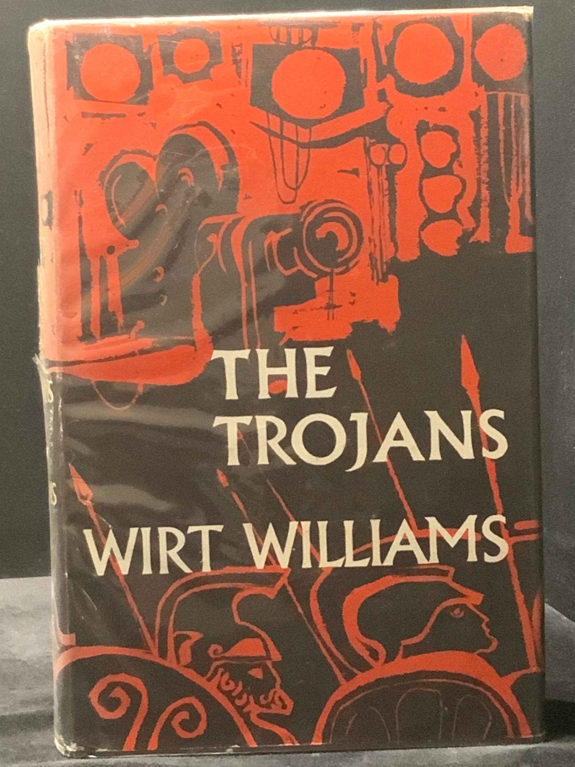 Book cover of 'The Trojans' by Wirt Williams with red illustrations on a black background