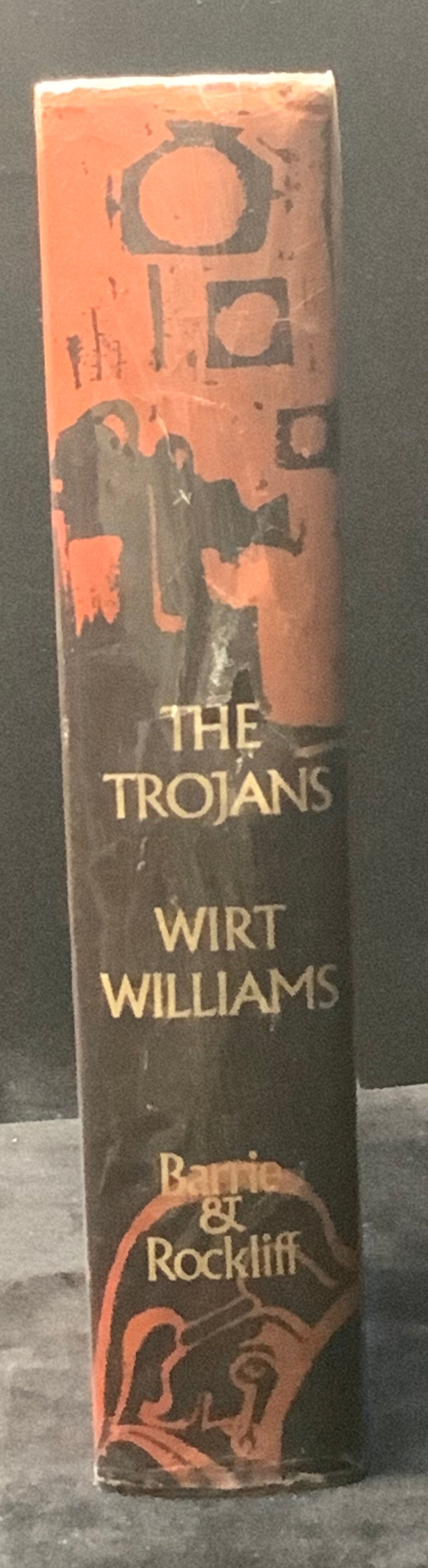 Book titled 'The Trojans' by Wirt Williams on a dark background