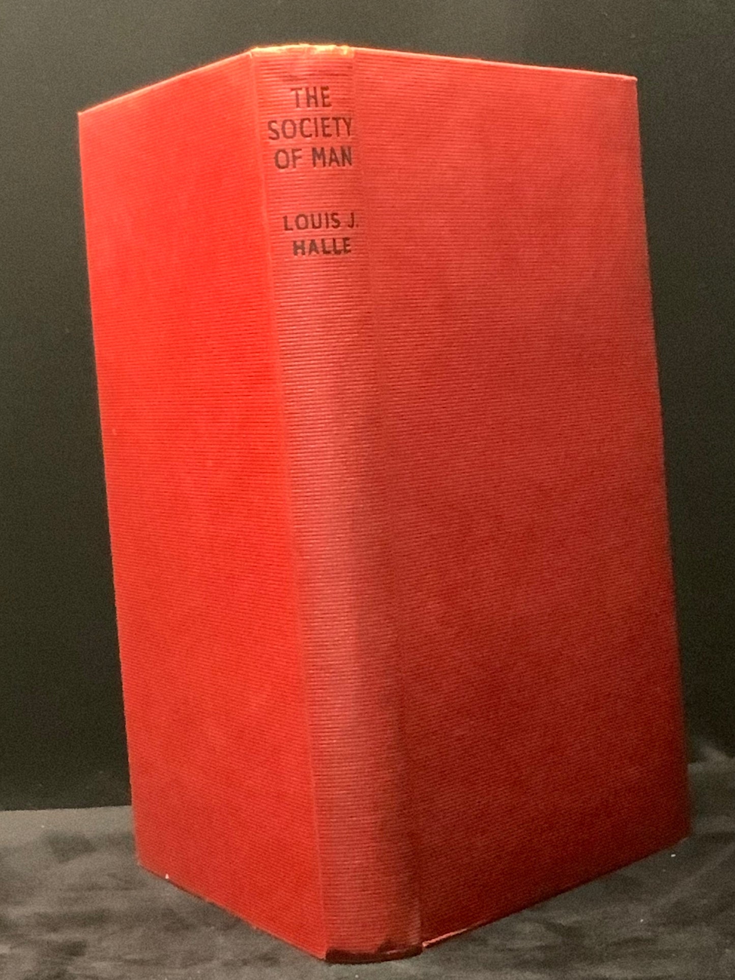 Red book titled 'The Society of Man' by Louis J. Halle on a dark background